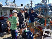 Eric is giving a boat tour and explanation about the different data acquisition​ systems to Steve, Jason, ​and Emily, the chase boat team from UH Hilo marine operation​s.